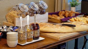 A breakfast spread with pastries, bread, and jars of jam.