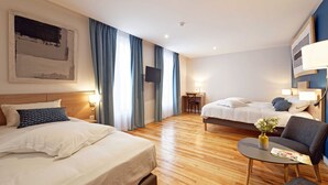 A hotel room with two beds, a desk, a chair, and a small table with a vase and magazine. - Contact Hôtel de la Gare et son restaurant Côte à Côte (Autun)