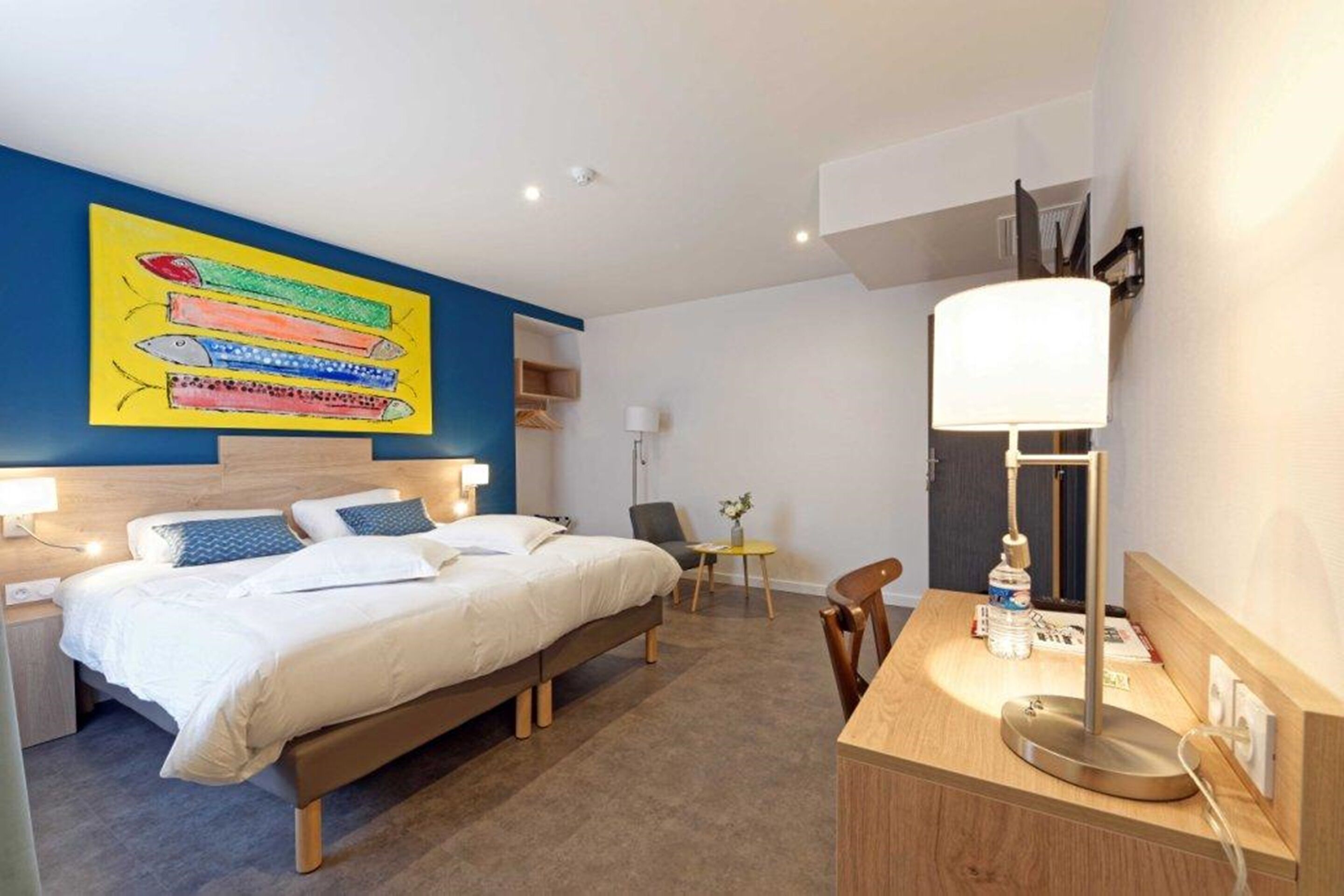 Una habitación de hotel moderna con una cama grande, mesitas de noche, un escritorio y una silla.
