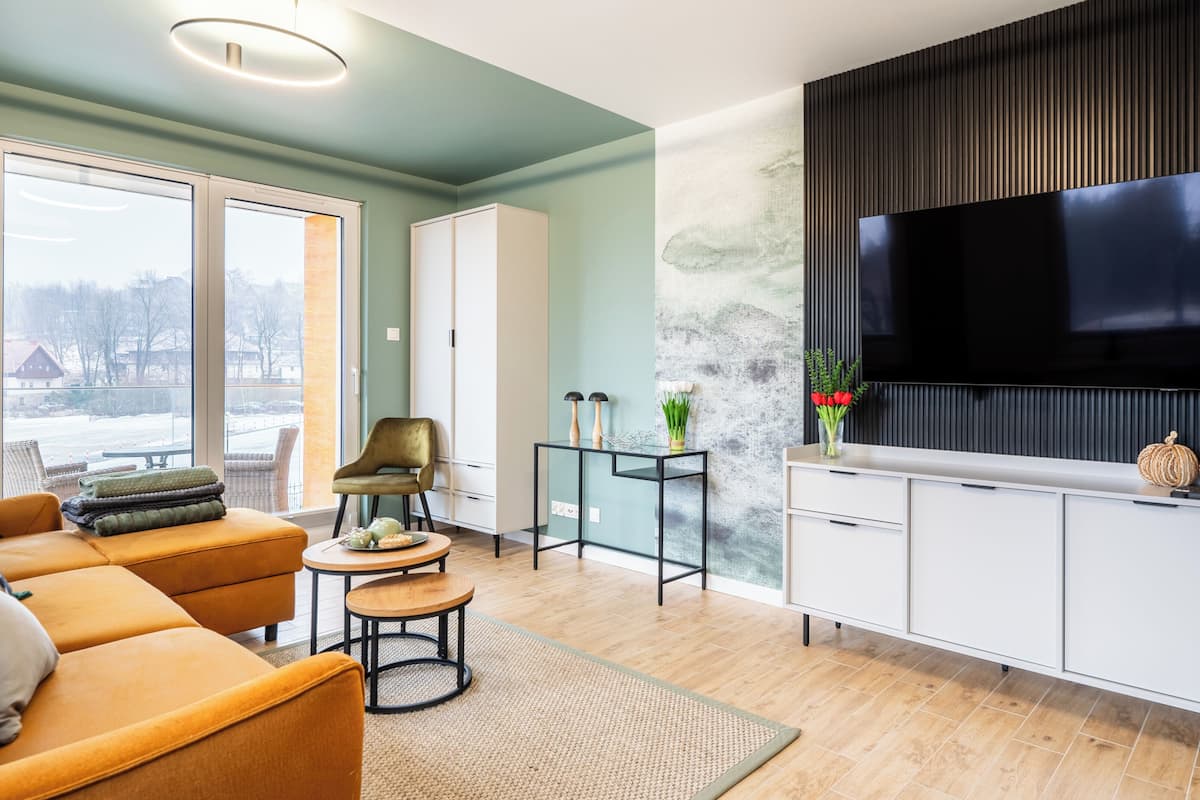Een moderne woonkamer met een bank, een fauteuil, een bijzettafeltje, een televisie en een kast.