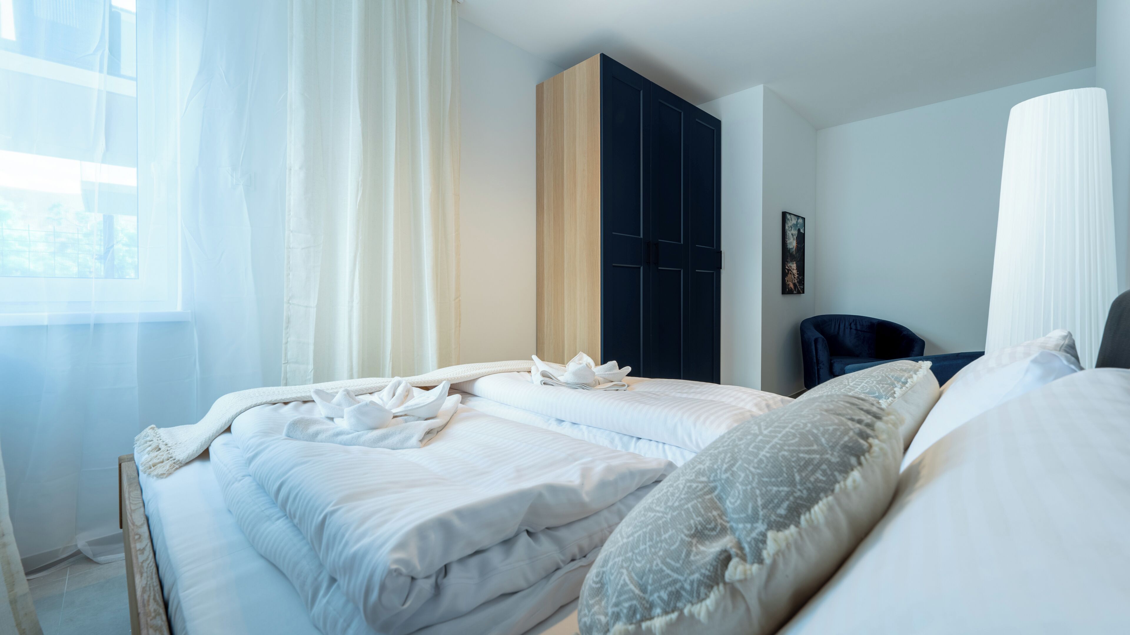 Ett hotellrum med två sängar, en garderob och ett fönster med gardiner.