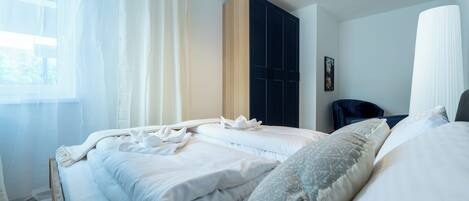 A hotel room with two beds, a wardrobe, and a window with curtains.
