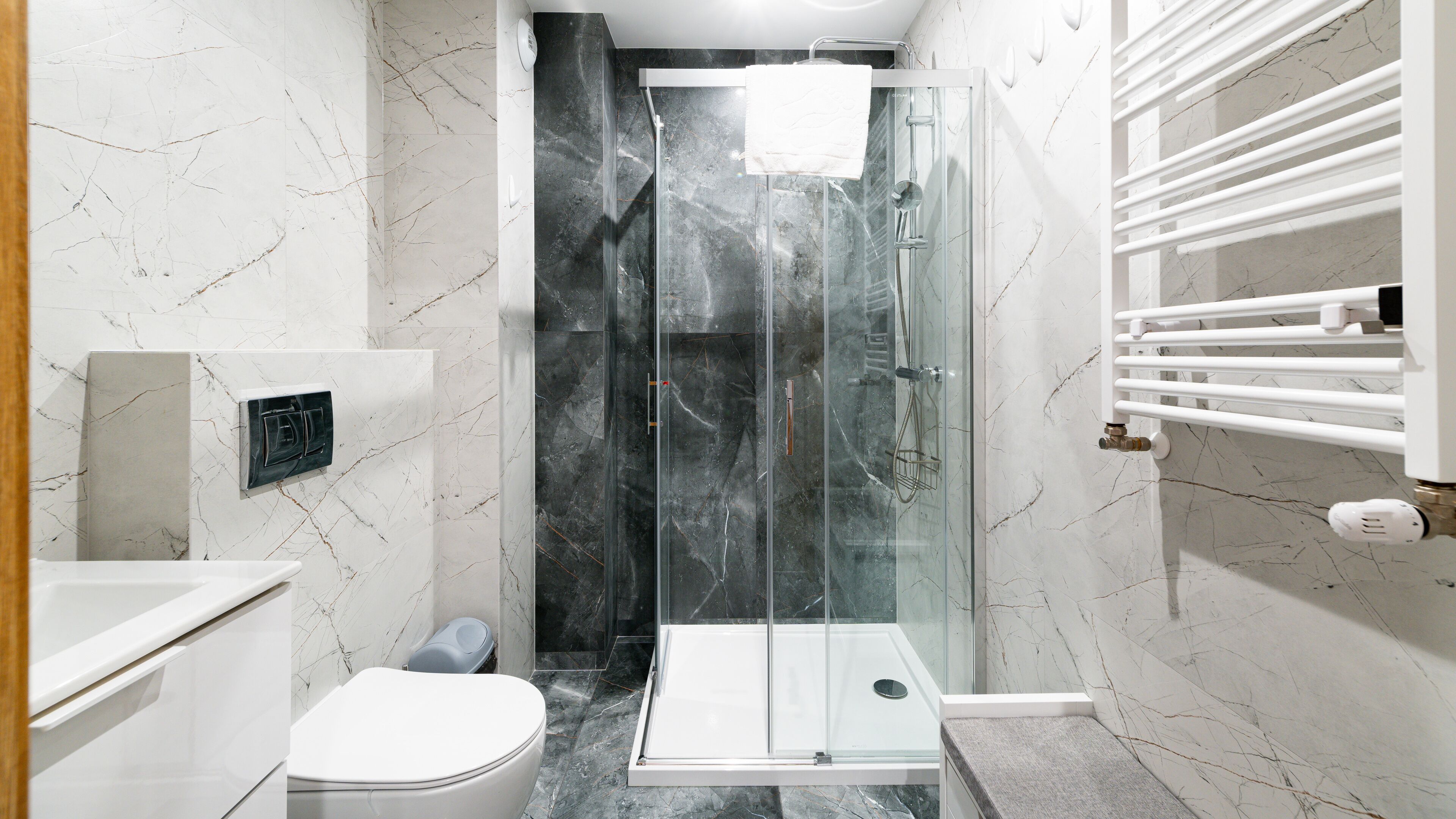 A modern bathroom with a glass-enclosed shower, a toilet, and a white sink.