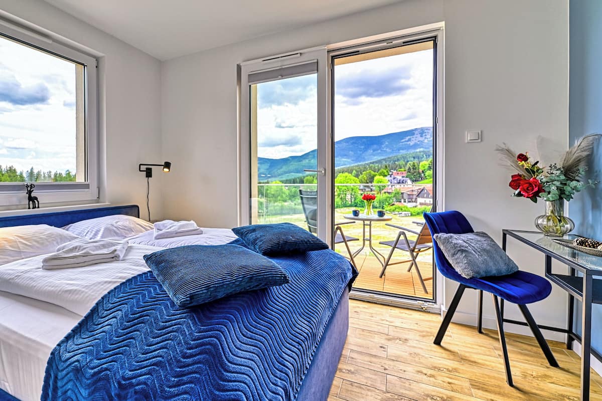 Een slaapkamer met een bed, een stoel, een tafel en uitzicht op het landschap.