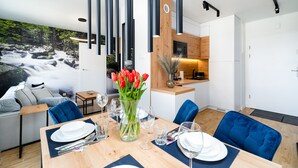Een moderne eethoek met een houten tafel gedekt voor vier personen, omringd door blauwe stoelen. Op de tafel staat een vaas met rode tulpen.