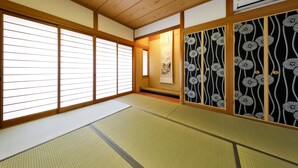 A traditional Japanese room with tatami flooring, sliding doors, and a decorative screen with floral patterns. - Residence inn Makinoyado (Osaka)