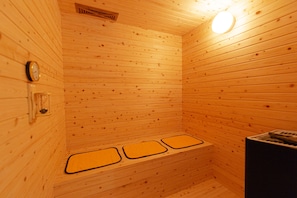 Un sauna en bois avec trois bancs et une horloge visible au mur.