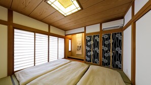 A traditional Japanese room with tatami flooring, sliding doors, and a ceiling fan. - Residence inn Makinoyado (Osaka)
