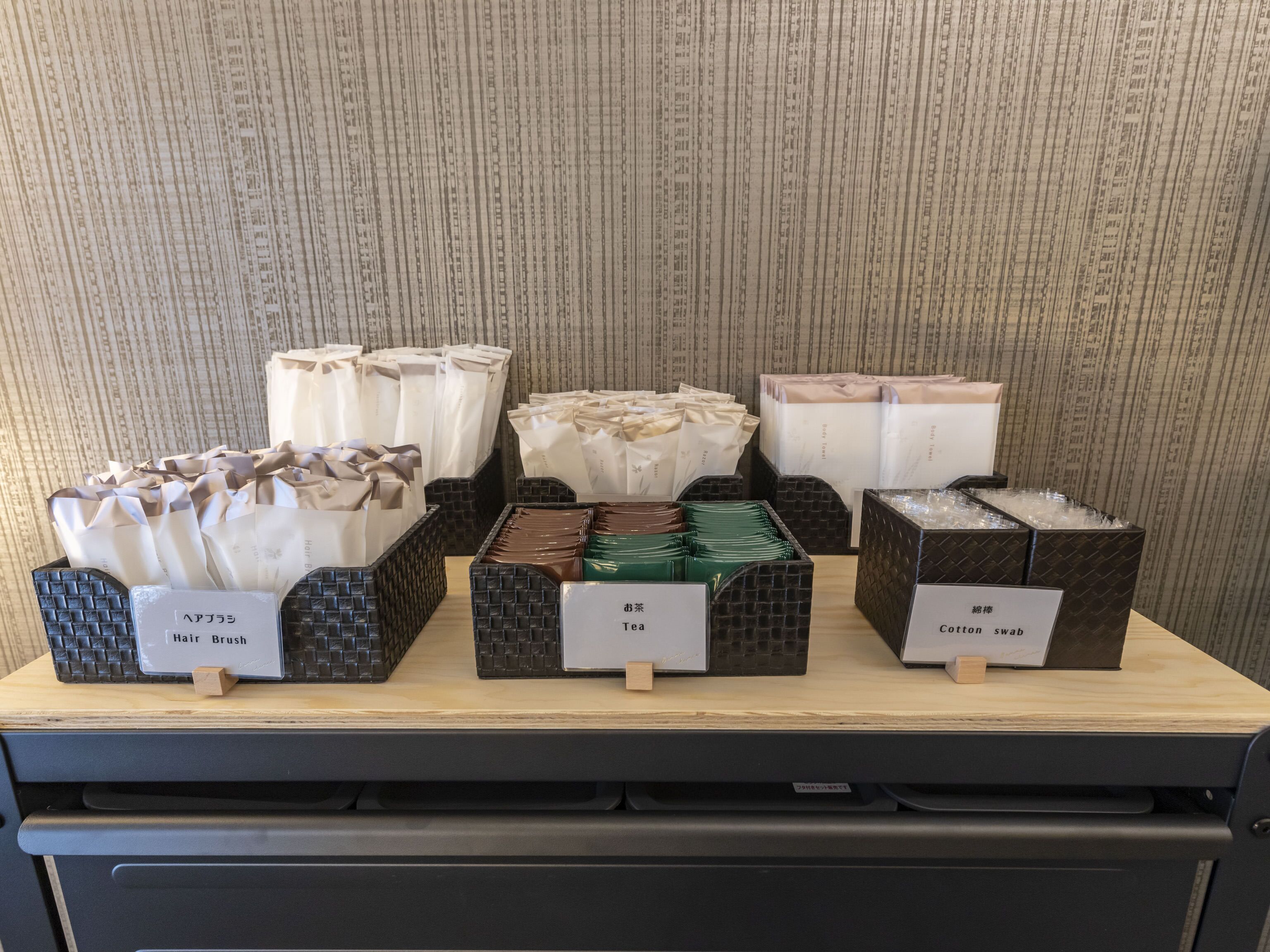 A display of hair brushes and cotton swabs on a wooden table with a striped wallpaper background.