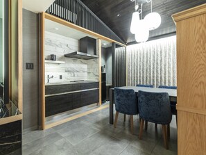 A modern kitchen with dark wood cabinets, a marble backsplash, and a built-in stove. - Tabist kiki HOTEL KYOTO Sanjo Takakura (Kyoto)