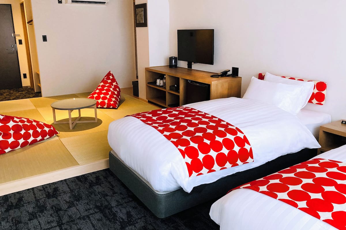 A hotel room with a bed, a TV, a desk, and a chair.