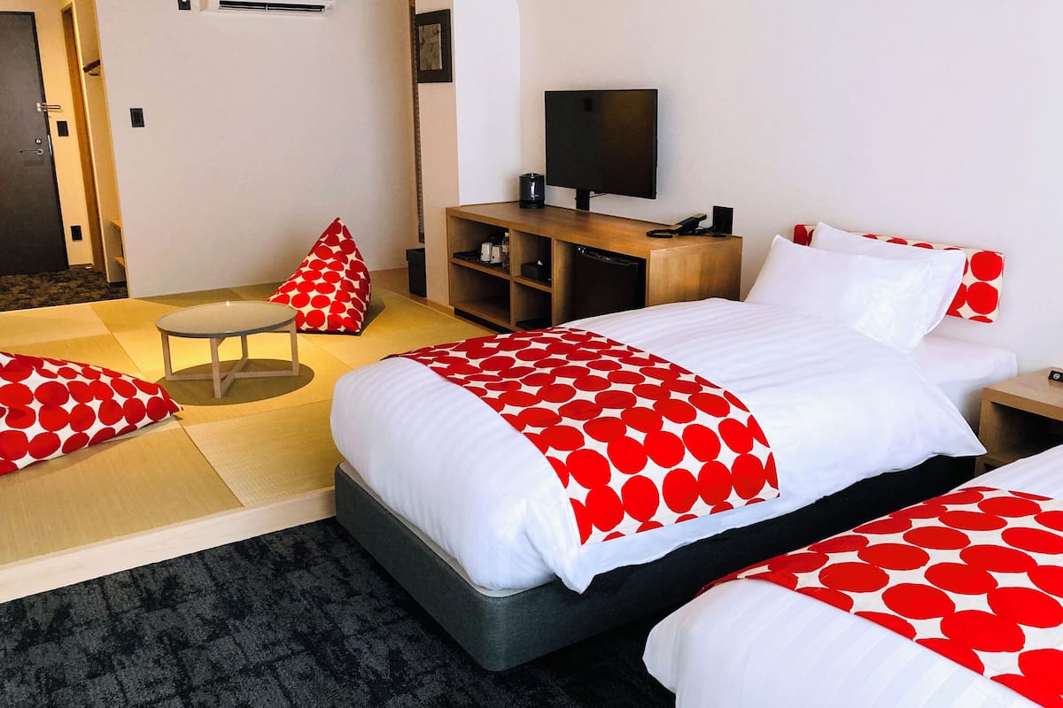 A hotel room with a bed, a TV, a desk, and a chair.
