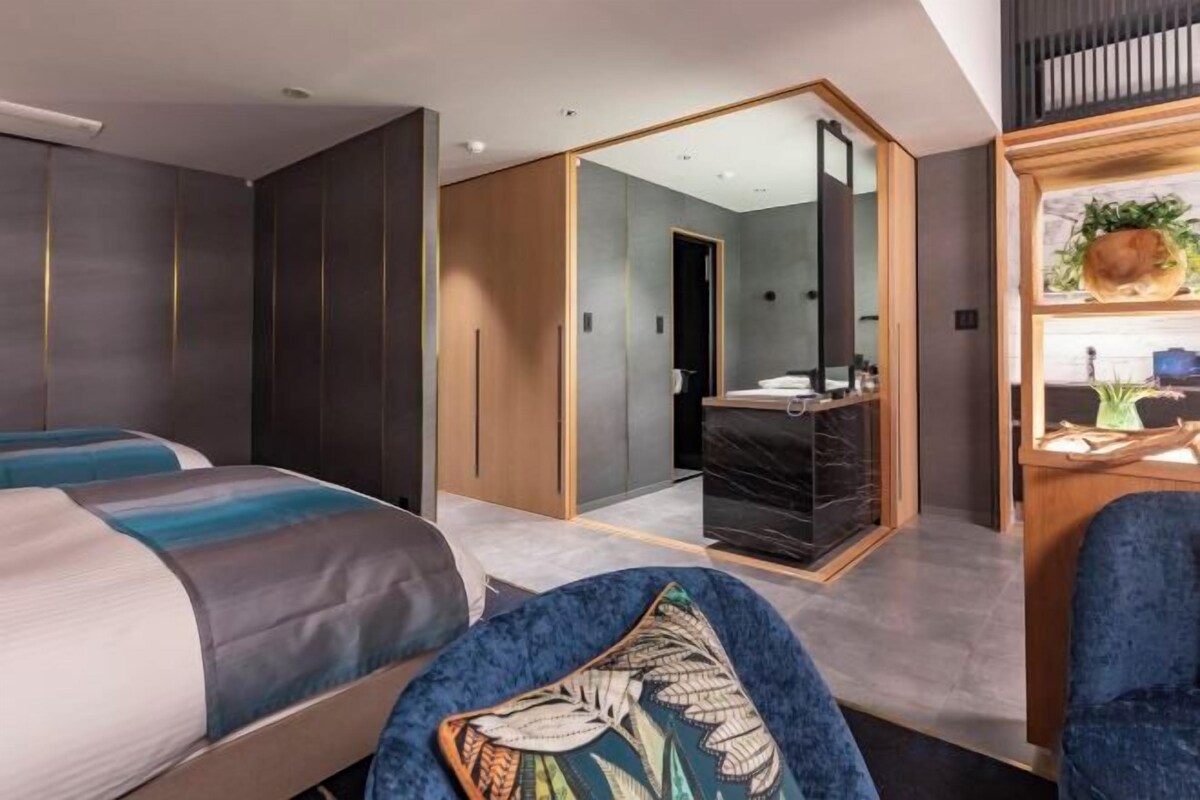 A modern hotel room with a bed, a desk, and a bathroom.