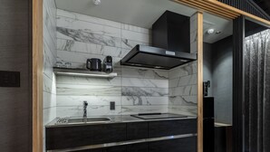 A modern kitchen with marble backsplash, black cabinetry, and a built-in stove.