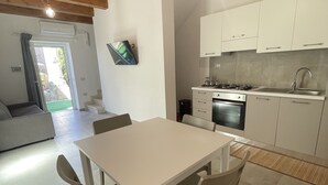 Une cuisine moderne avec des meubles blancs, une table à manger avec des chaises et un four encastré.