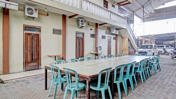 A long table with chairs, air conditioning units, and a staircase leading to an upper level.