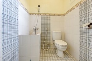 A bathroom with a white bathtub, a toilet, and a shower. - OYO 93660 New Family Hotel Syariah (Mungkid)