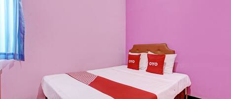 A single-bed room with a pink wall, white bedding, and red accents.