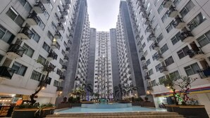 A high-rise residential building with multiple balconies, a central courtyard with a pool, and surrounding greenery. - Hotel O The Jarrdin Apartment By Putra Homestay Property (Bandung)