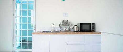 A kitchen with a microwave, sink, and dish rack.