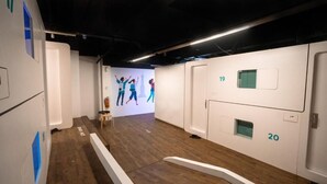 A corridor with wooden flooring, white walls, and numbered doors.