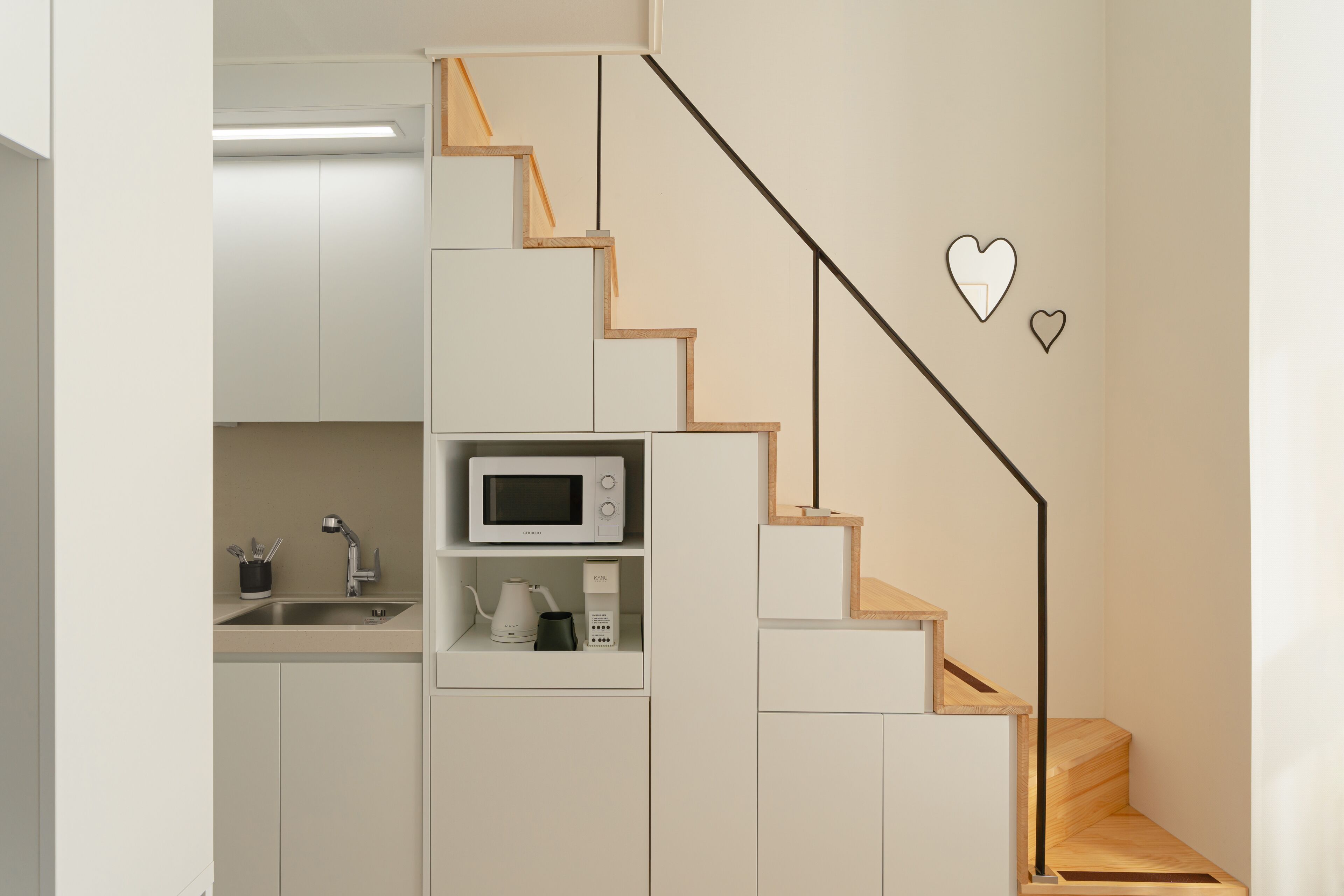 A modern kitchen with built-in appliances, a wooden staircase, and minimalist design.