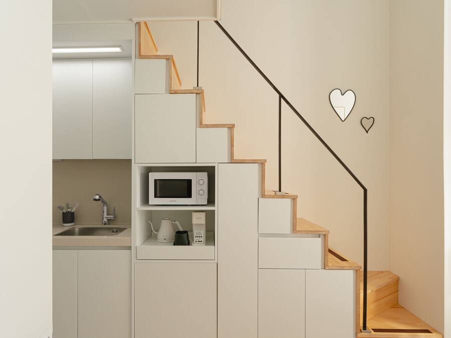 A modern kitchen with built-in appliances, a wooden staircase, and minimalist design.