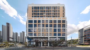 Un edificio moderno de varios pisos con una fachada de ventanas enrejada, techo plano y un amplio acceso.