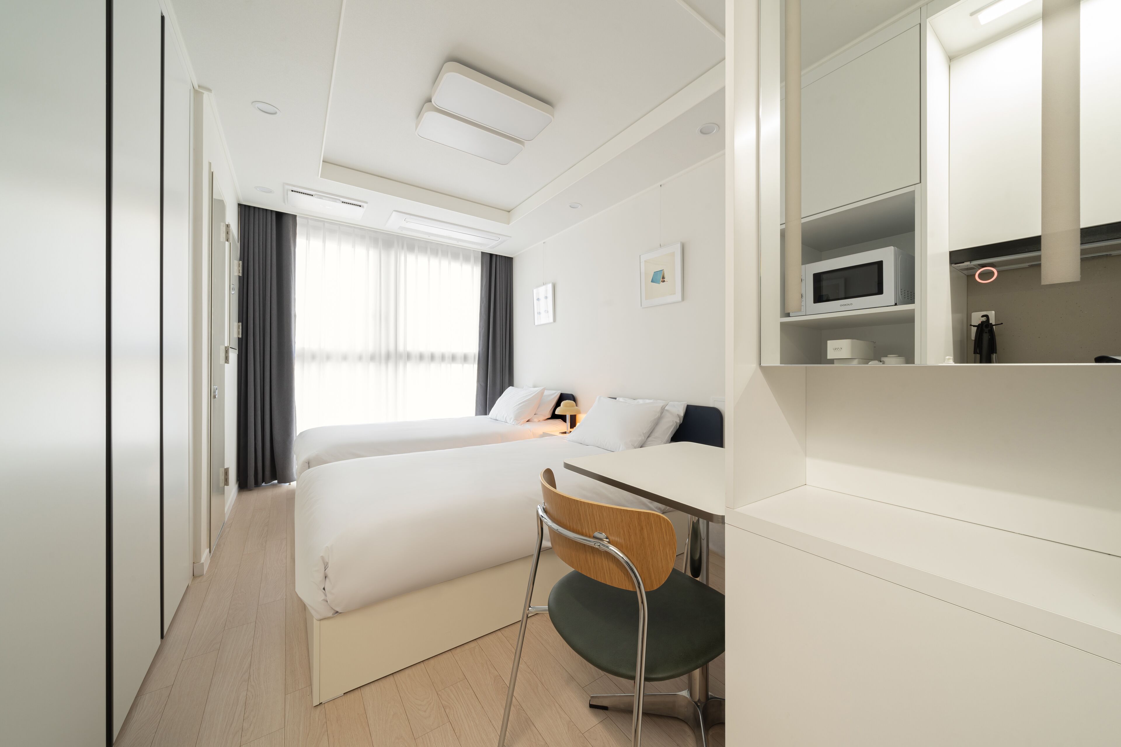 A hotel room with a bed, a desk, a chair, a microwave, and a large mirror.
