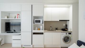 Una kitchenette moderna y funcional, equipada con microondas, cafetera y lavadora.