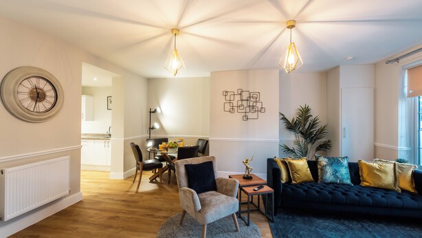 A modern living room with a dark blue sofa, a round rug, and a dining area with a table and chairs. - Seymour  (Southampton)