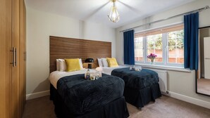 A hotel room with two beds, a wooden headboard, a large window with curtains, and a ceiling fan. - Seymour  (Southampton)