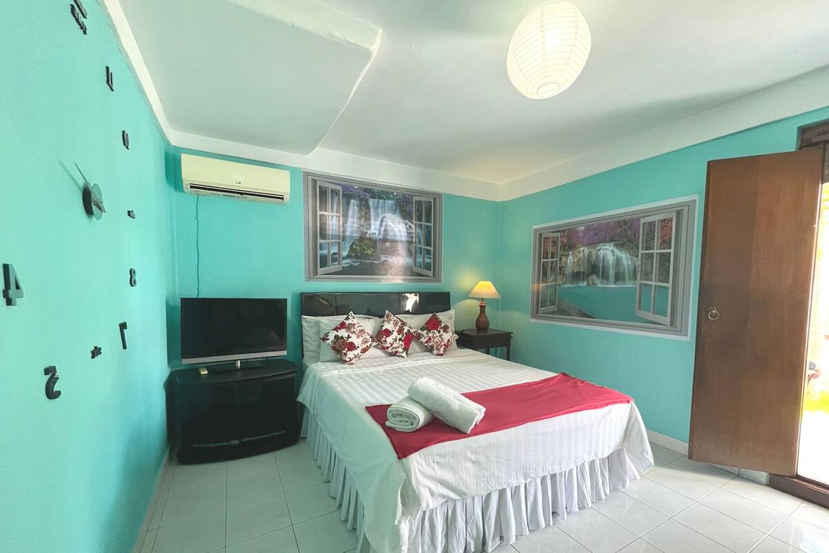 Un dormitorio con cama, televisor y ventana con vistas a una cascada.