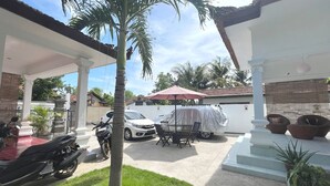 Un espacio al aire libre cubierto con un coche, una motocicleta y una parrilla para barbacoa también cubierta.