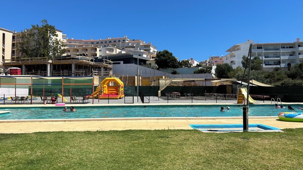 A swimming pool with inflatable slides and a grassy area in front.