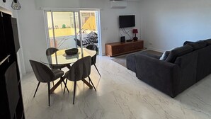 A modern living room with a dining area, a sofa, and a TV.
