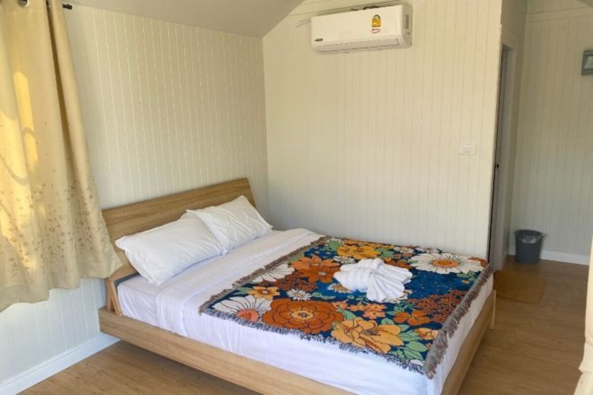 Una cama individual con colcha estampada, cabecera de madera y almohada blanca.