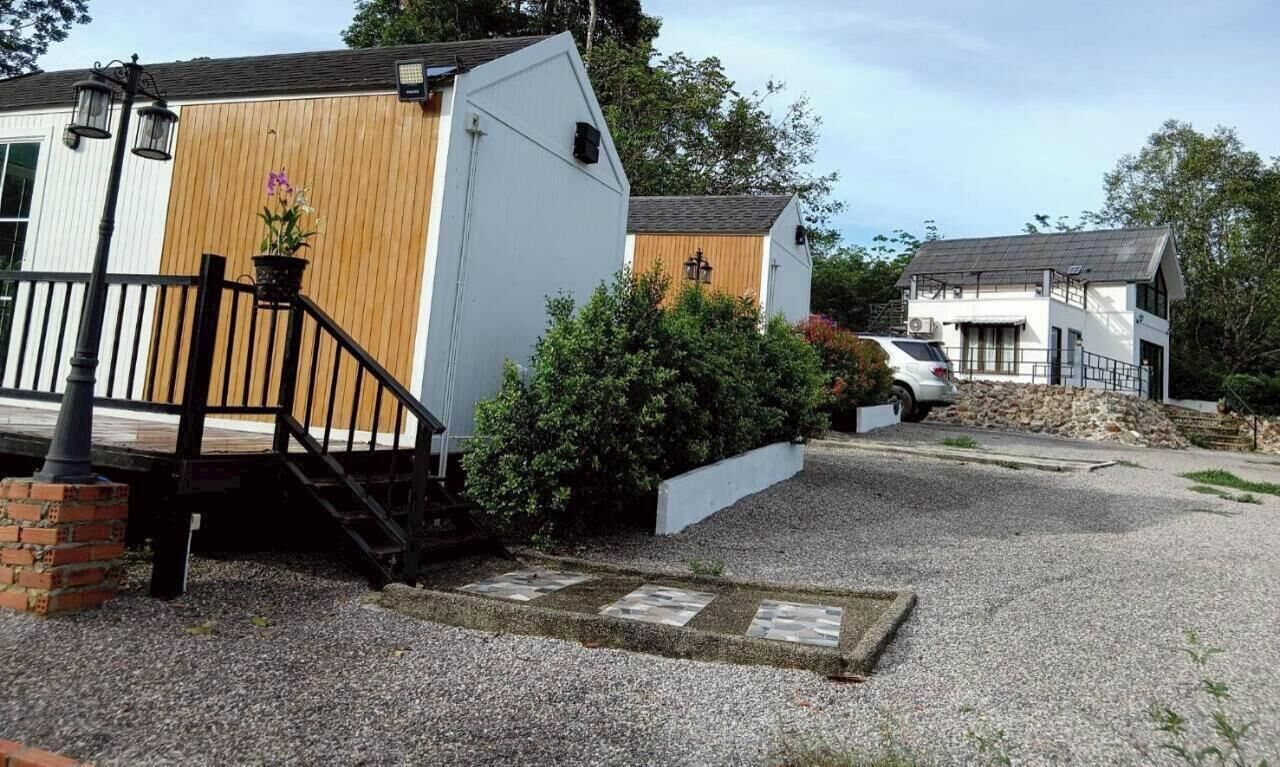 A residential property with a gravel driveway, a wooden deck, and a white building with a sloped roof.