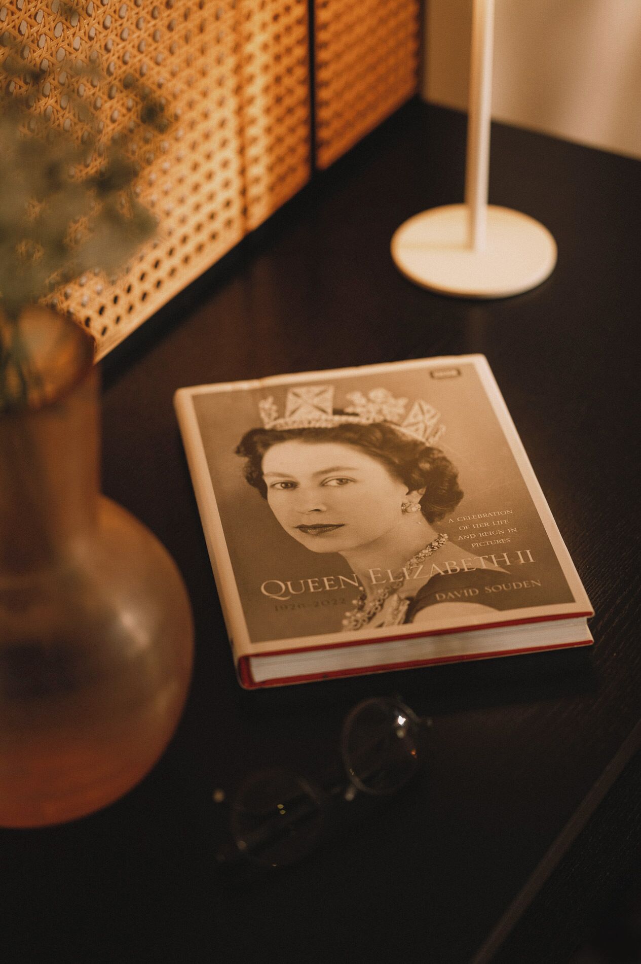 Een boek met de titel 'Queen Elizabeth II' op een donker houten tafel.