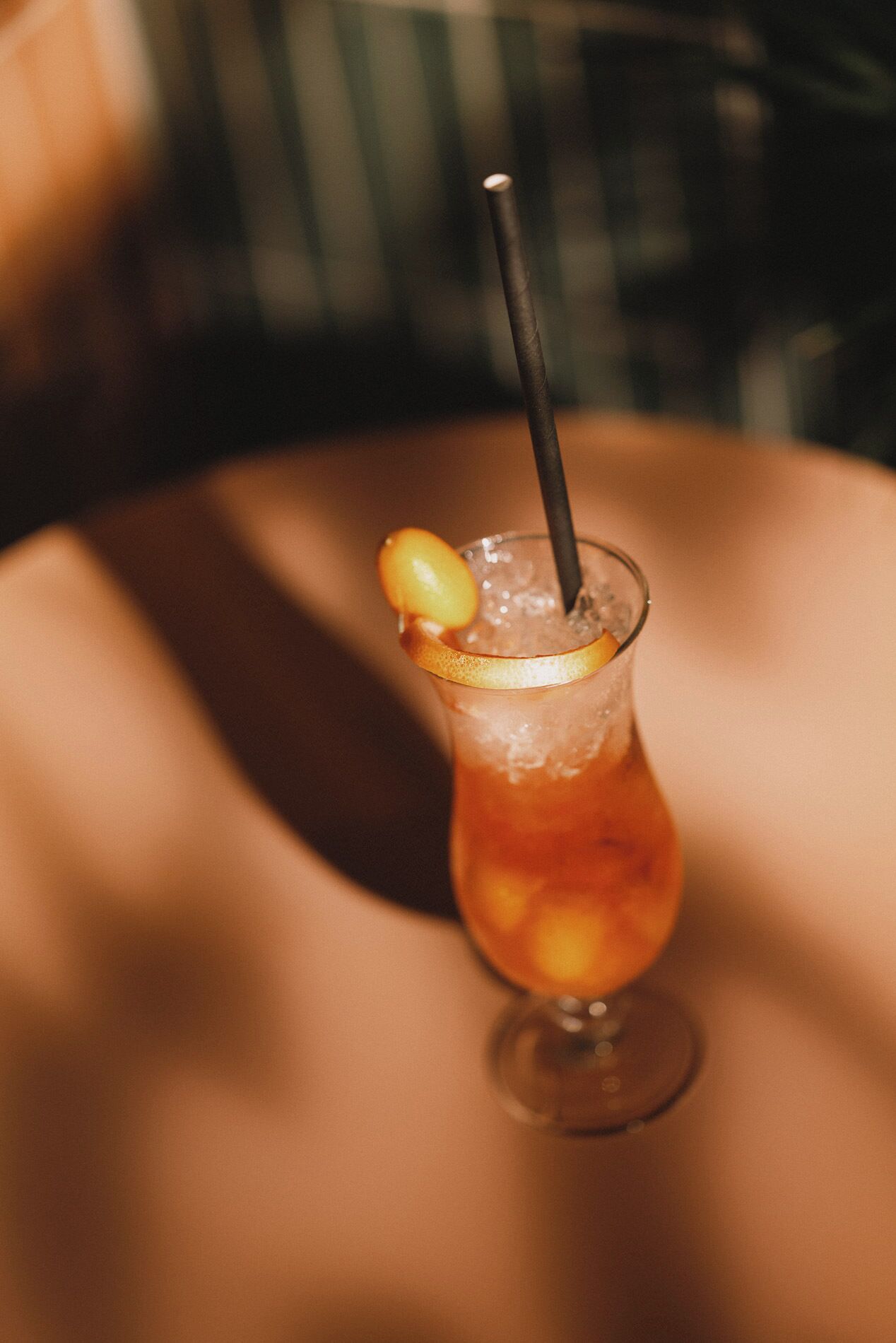 Un verre à cocktail avec une tranche de citron et une paille, posé sur une table.