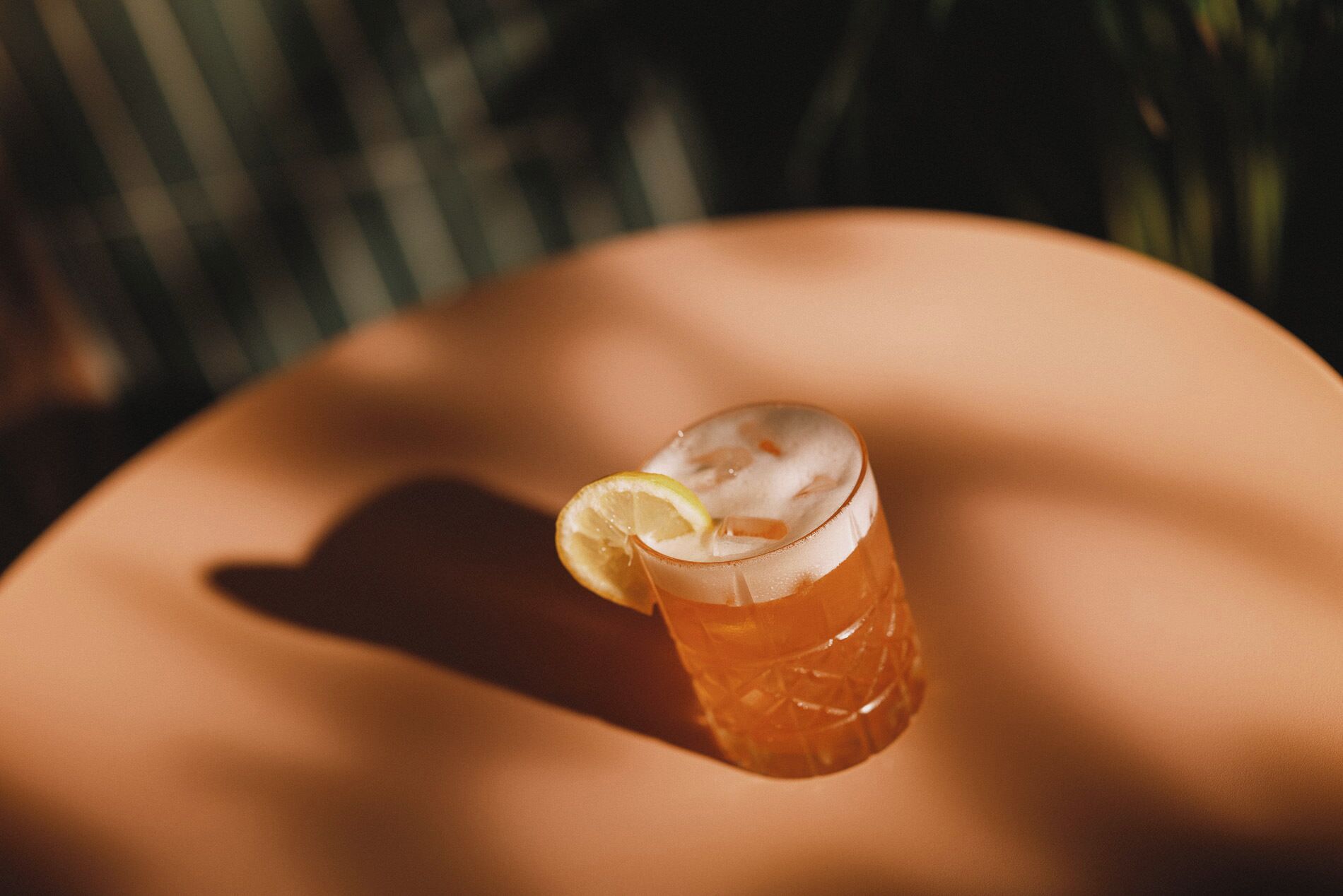 A glass of iced tea with a lemon slice on a reflective surface.