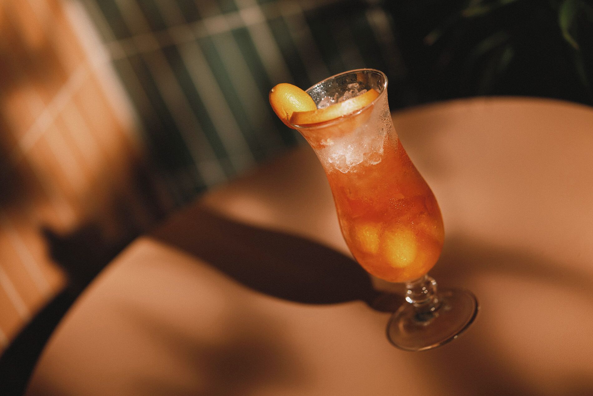 Ein Cocktailglas mit Eiswürfeln und einer Zitronenscheibe auf einem Tisch.