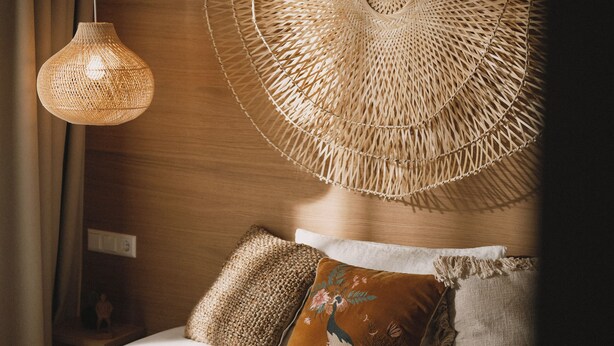 A bedroom with a bed, a woven wall hanging, and a hanging light fixture. - 2Places Soul (Loerrach)