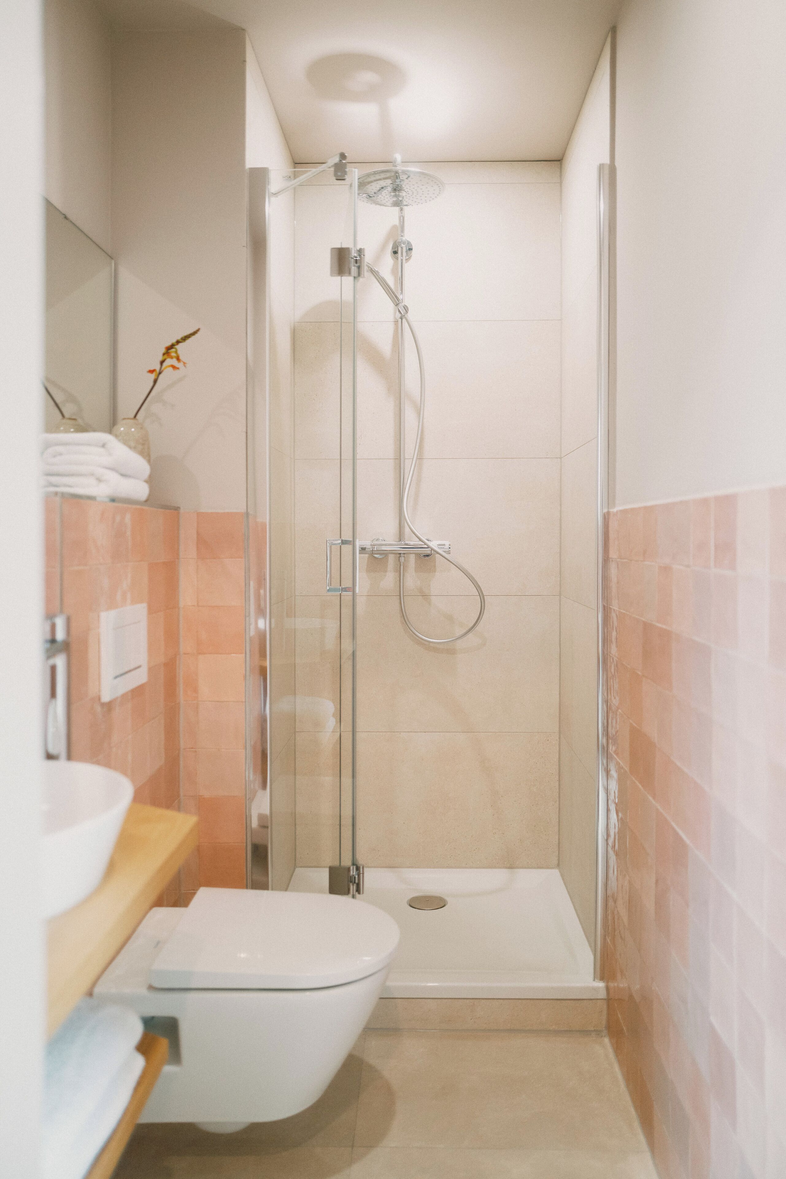 A modern bathroom with a glass-enclosed shower, a white toilet, and a sink with a mirror above it.