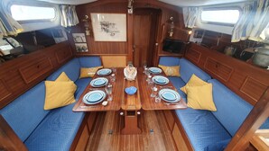 Un coin repas avec une table en bois dressée pour quatre personnes, des sièges rembourrés de couleur bleue et un tableau encadré accroché au mur.