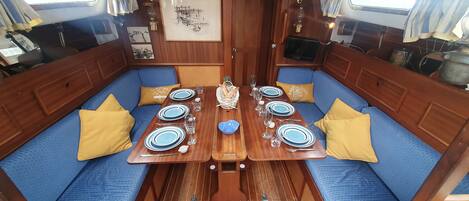 A dining area with a wooden table set for four, blue cushioned seating, and a framed picture on the wall.