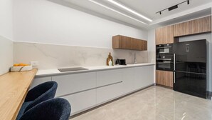 Een moderne keuken met een marmeren aanrechtblad, houten kastjes en een zwarte koelkast.