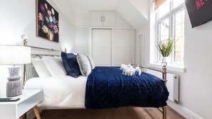 Une chambre à coucher bien rangée, avec un lit, une table de chevet, une lampe et une fenêtre donnant sur un beau paysage.