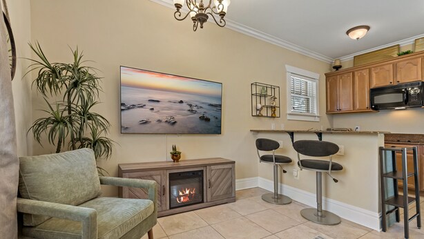 Ein Wohnzimmer mit Kamin, einem großen Gemälde, einer Bar und einer Küche im Hintergrund.