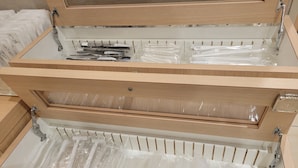 Een houten lade met verschillende vakken, elk gevuld met plastic verpakte voorwerpen.